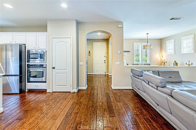 a large living room with stainless steel appliances wooden floors and large window