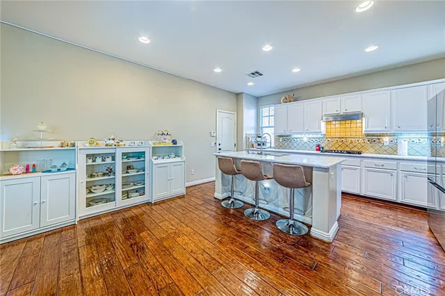 a kitchen with stainless steel appliances a stove a sink a oven with white cabinets and wooden floor