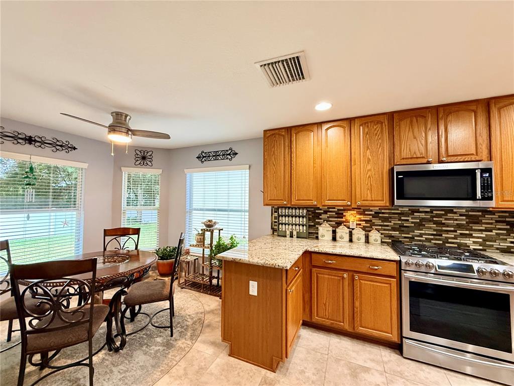 16296 Southwest 15th Court Ocala, FL 34473 - Photo 20 of 70 a kitchen with stainless steel appliances kitchen island granite countertop a stove top oven a sink dishwasher a dining table and chairs with wooden floor