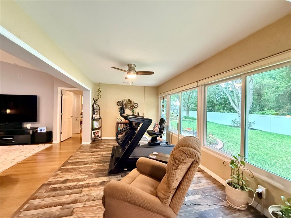 16296 Southwest 15th Court Ocala, FL 34473 - Photo 34 of 70 a living room with furniture floor to ceiling window and a flat screen tv