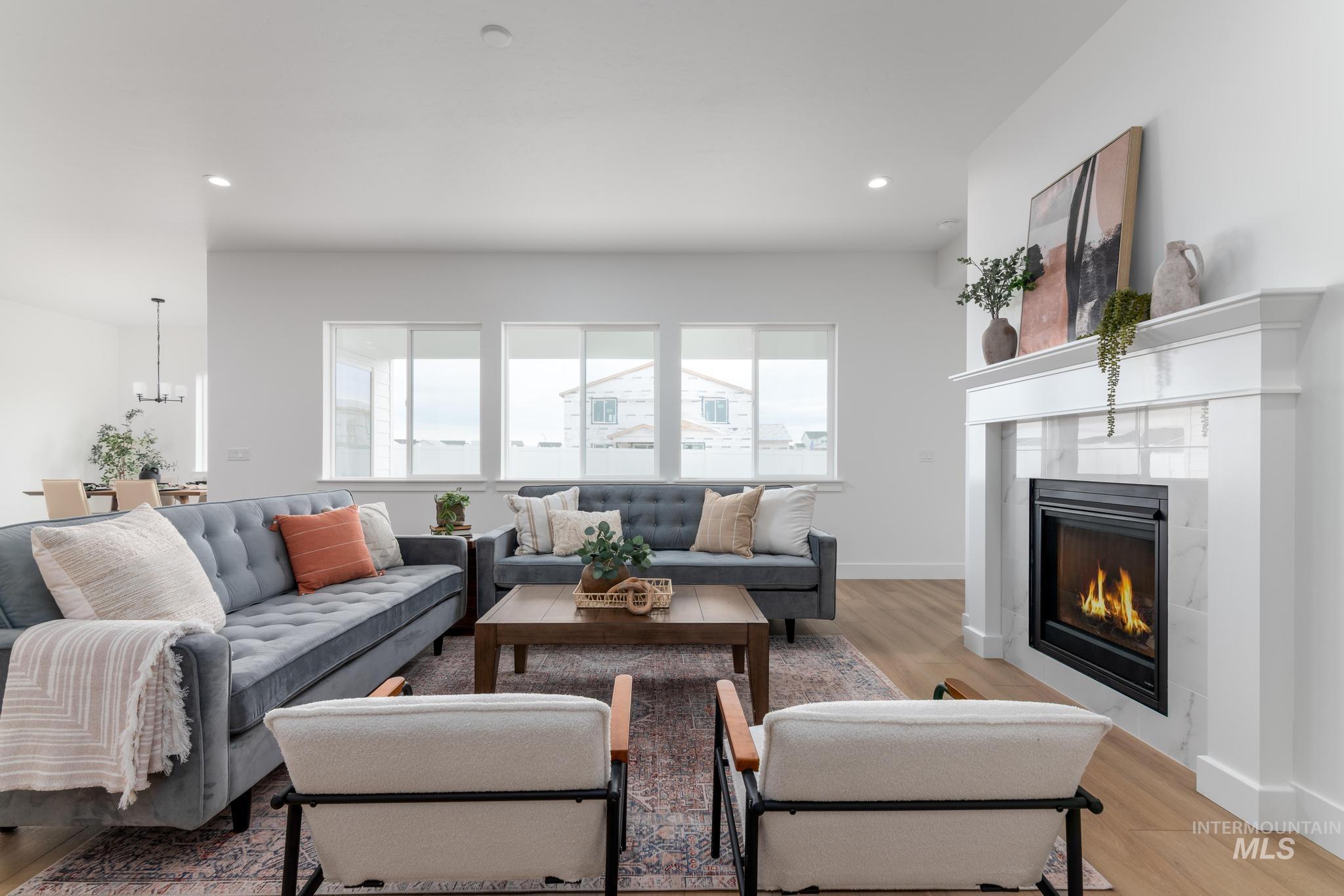 8569 South Silver Smog Way Meridian, ID 83642 - Photo 2 of 14 Living room with light wood-style floors, a glass covered fireplace, and suspended lighting