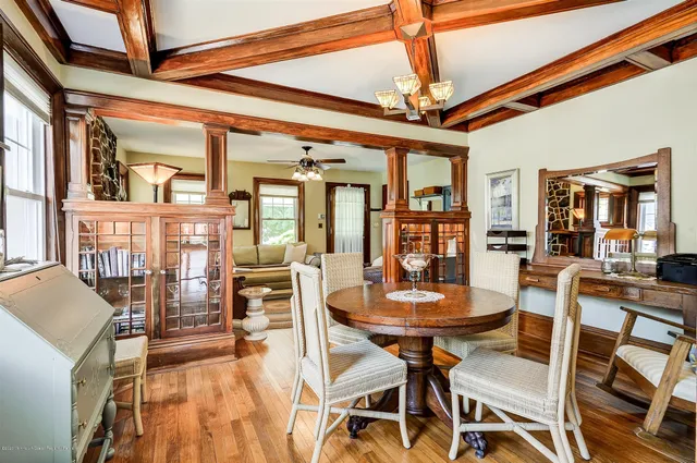a dining room with wooden floor a chandelier a wooden table and chairs