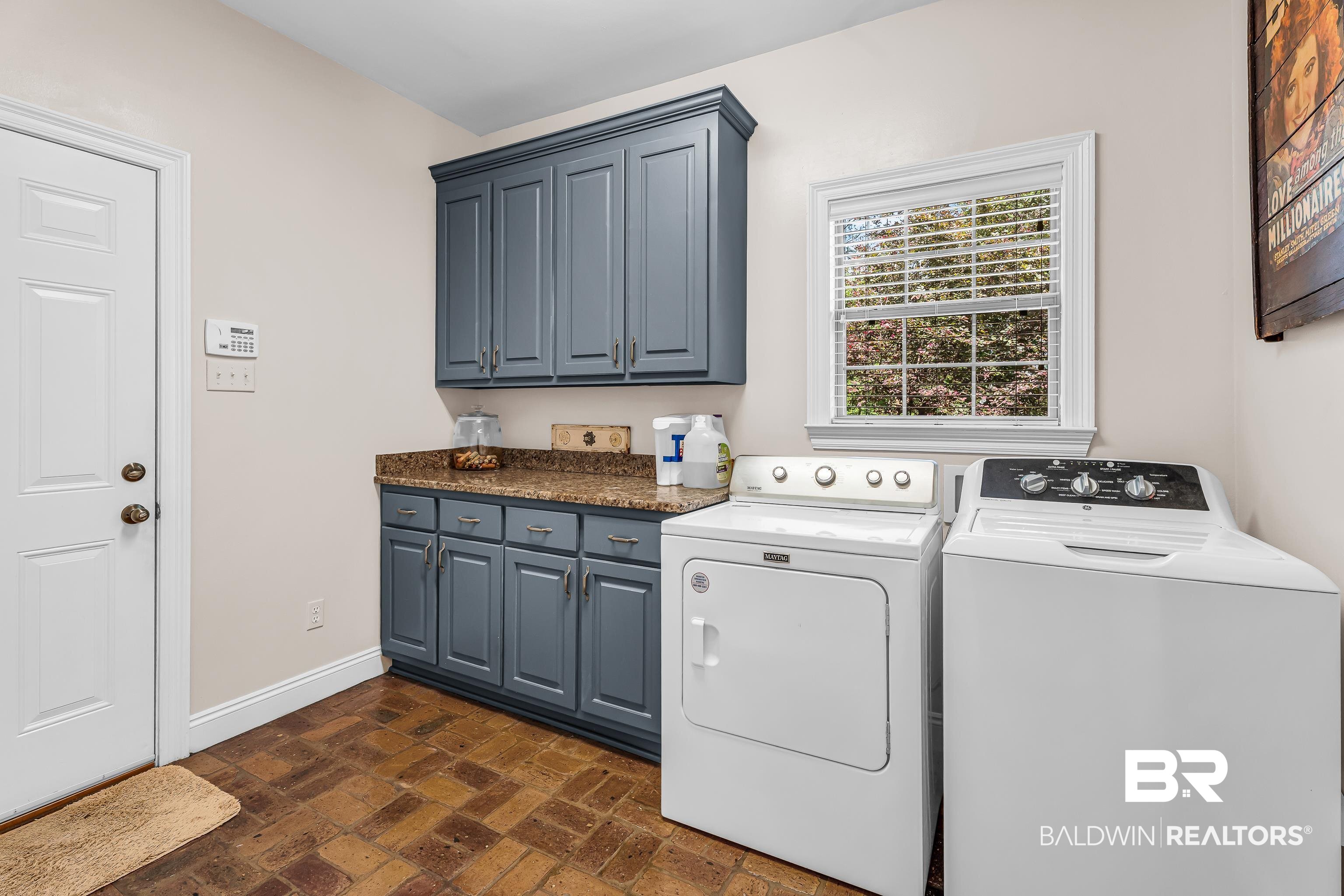 7014 Blakeley Road Daphne, AL 36527 - Photo 27 of 45 Utility room featuring blue cabinetry, a light-colored countertop, and a window with blinds