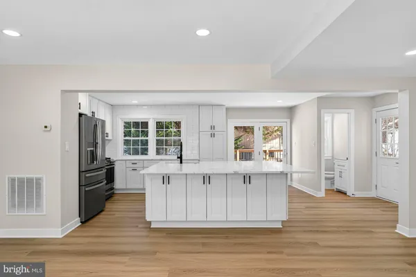 a kitchen with stainless steel appliances granite countertop a stove top oven a sink dishwasher and a refrigerator with wooden floor