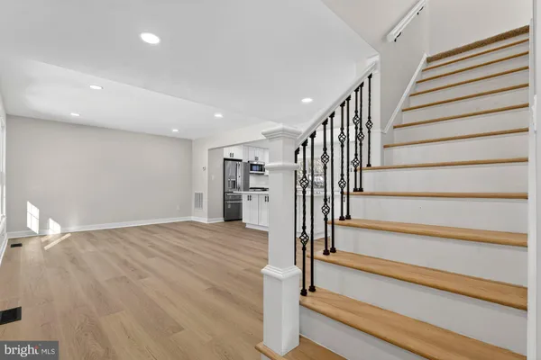 a view of an empty room with wooden floor and a kitchen