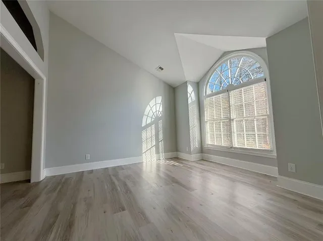 an empty room with wooden floor fan and windows