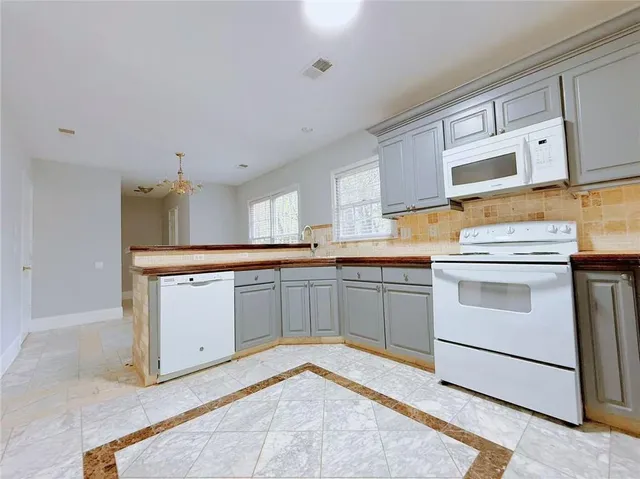 a kitchen with granite countertop white cabinets and white appliances