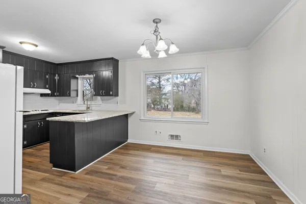 a kitchen with stainless steel appliances granite countertop a refrigerator a sink dishwasher a stove and white countertops with wooden floor