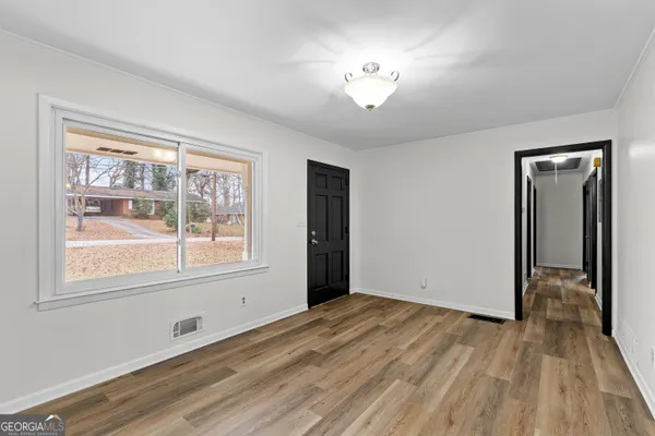 a view of an empty room with wooden floor and a window