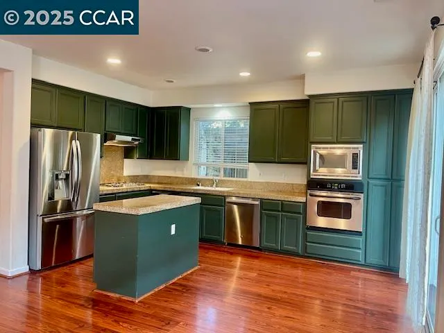 a kitchen with stainless steel appliances granite countertop a refrigerator and a stove