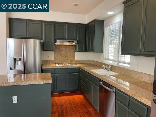 a kitchen with stainless steel appliances granite countertop a sink and a refrigerator