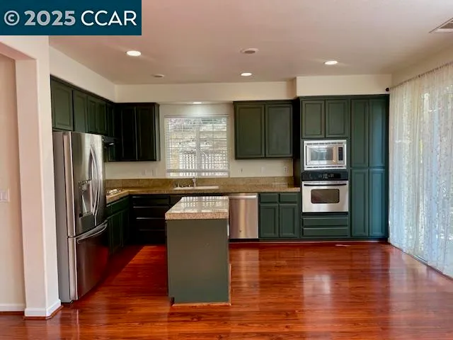 a kitchen with stainless steel appliances granite countertop a refrigerator a sink and a stove
