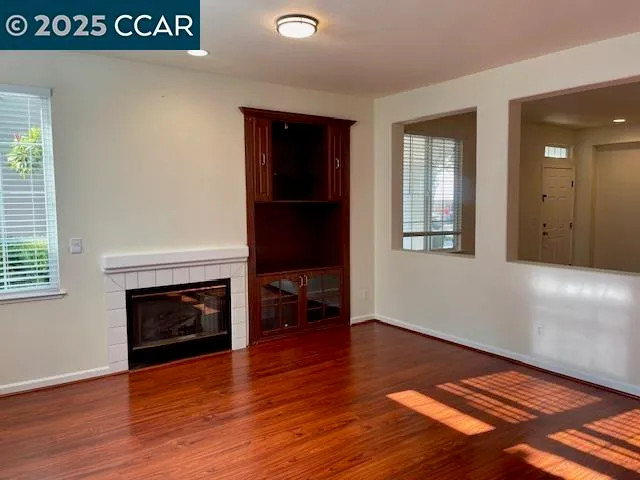 an empty room with wooden floor fireplace and windows