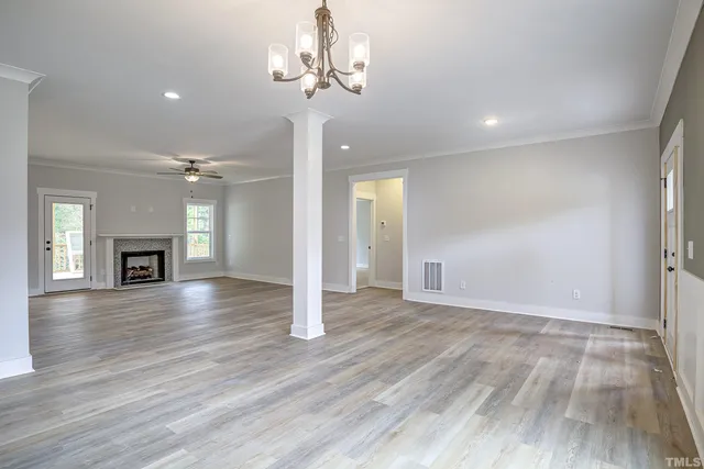 a view of an empty room and kitchen with hardwood floor
