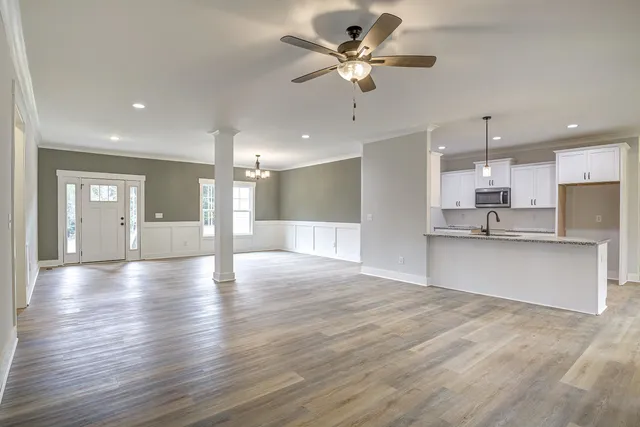 an empty room with a chandelier fan and windows