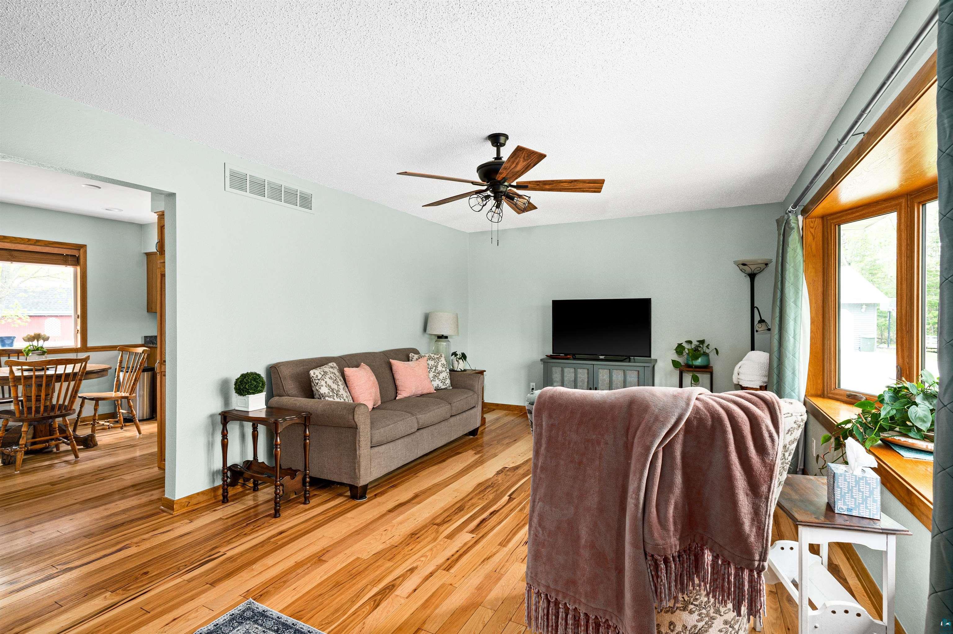 6908 Morris Thomas Road Cloquet, MN 55720 - Photo 11 of 41 Living room featuring ceiling fan, light hardwood / wood-style floors, and a textured ceiling