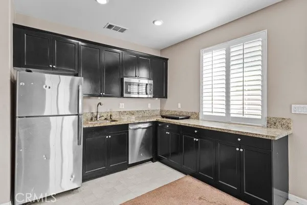 a kitchen with stainless steel appliances granite countertop a sink a stove a refrigerator and cabinets