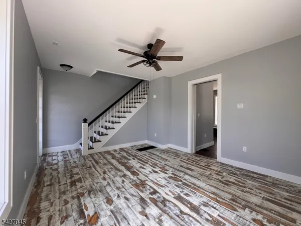 a view of an empty room with a ceiling fan and staircase