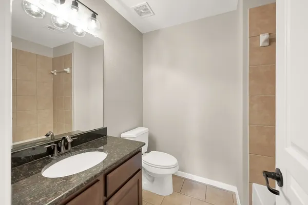a bathroom with a granite countertop sink toilet a mirror and a shower