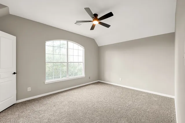 an empty room with ceiling fan and windows