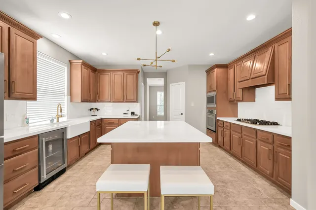 a large kitchen with stainless steel appliances kitchen island granite countertop a stove a sink dishwasher and a refrigerator with wooden cabinets