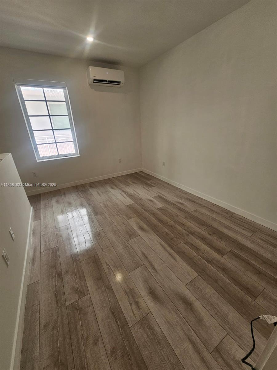 1610 Euclid Avenue, Unit A107 Miami Beach, FL 33139 - Photo 7 of 14 an empty room with wooden floor and windows