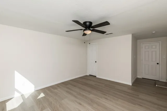 a view of a room with wooden floor and a ceiling fan