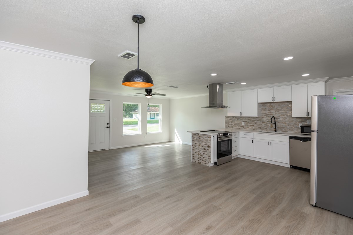 5260 Landry Lane Beaumont, TX 77708 - Photo 7 of 25 a kitchen with stainless steel appliances granite countertop a refrigerator a sink dishwasher a stove and white cabinets with wooden floor