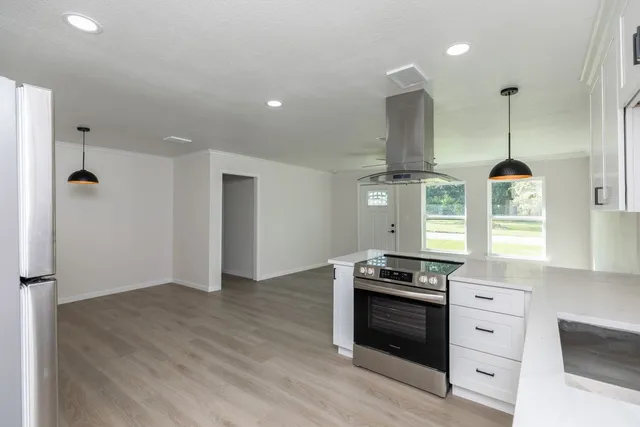 a kitchen with granite countertop a stove and a wooden floors