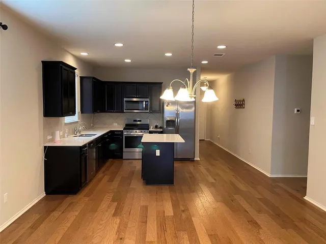 a large kitchen with stainless steel appliances granite countertop a sink a stove and a wooden floors