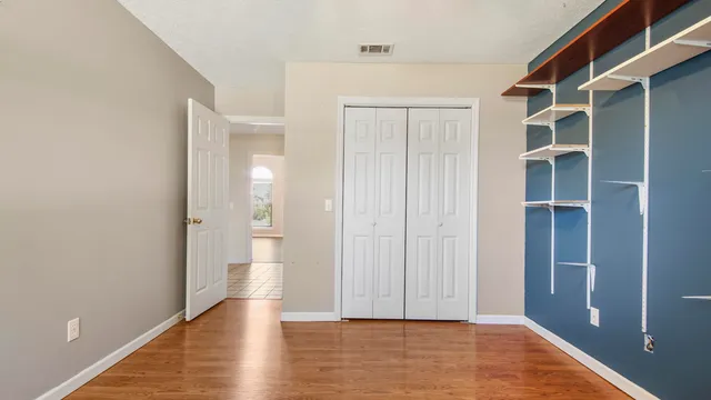 a view of an empty room with wooden floor and closet