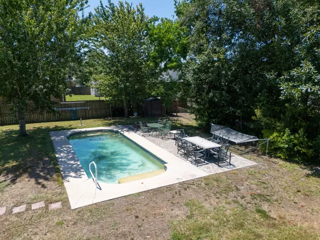 a view of a backyard with a small pool and trees