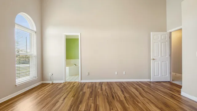 an empty room with wooden floor and windows