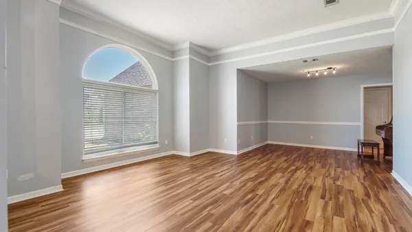 a view of empty room with wooden floor and fan