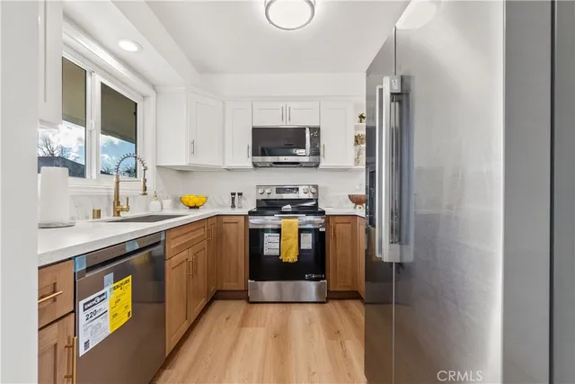 a kitchen with stainless steel appliances granite countertop a refrigerator a stove top oven a sink and dishwasher