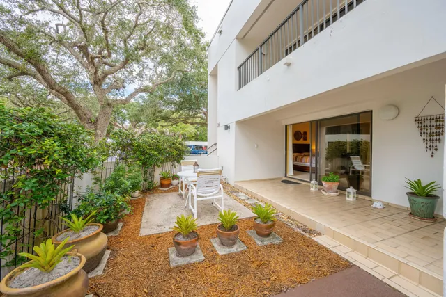 a view of a patio with table and chairs potted plants and large tree