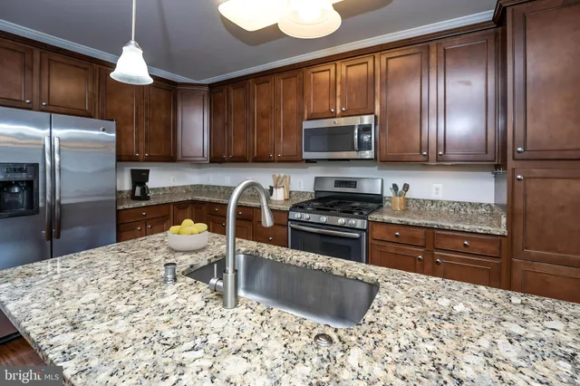 a kitchen with granite countertop a refrigerator stove top oven a sink and dishwasher