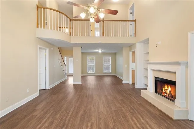 a view of an empty room with wooden floor and a fireplace