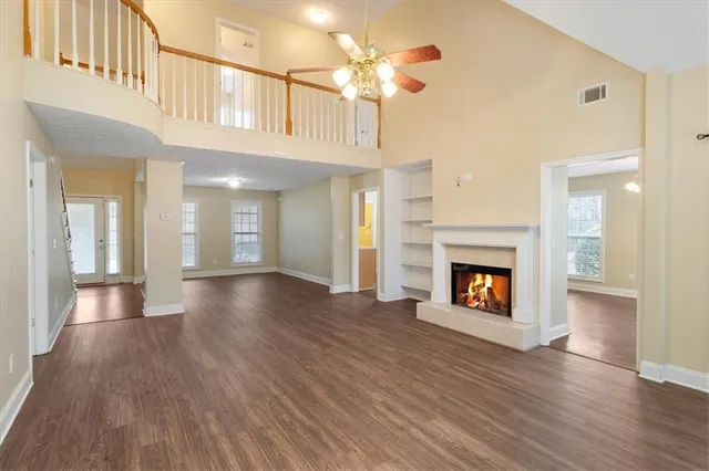 a view of an empty room with wooden floor fireplace and a window