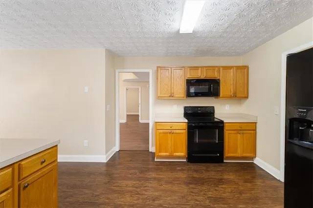 a kitchen with granite countertop a stove top oven a sink dishwasher and a refrigerator with wooden floor