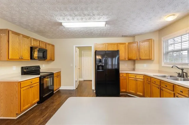 a kitchen with stainless steel appliances granite countertop a refrigerator a stove top oven a sink dishwasher and wooden cabinets