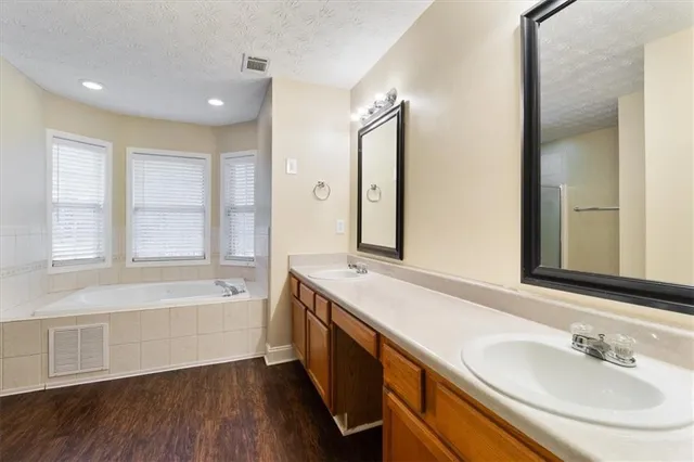 a spacious bathroom with a tub sink and mirror