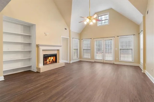 an empty room with wooden floor fireplace and windows