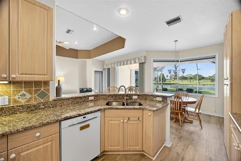 a kitchen with stainless steel appliances granite countertop a stove a sink dishwasher and white cabinets with wooden floor