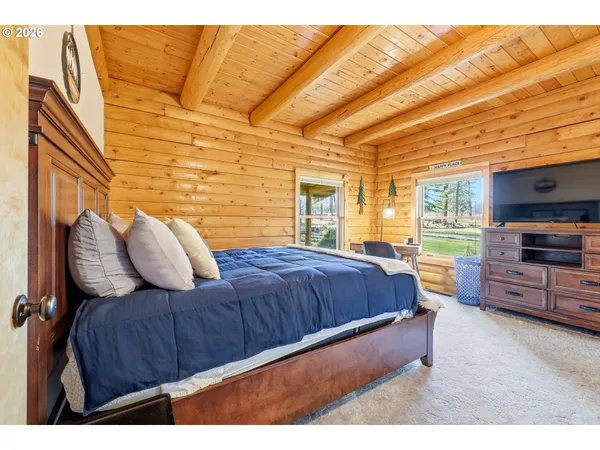 a spacious bedroom with a bed and wooden floor