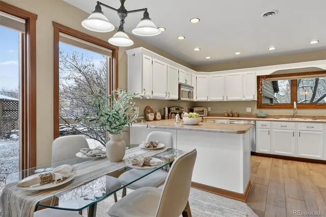 a kitchen with granite countertop a stove a sink a dining table and chairs