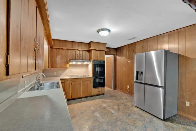 a kitchen with granite countertop stainless steel appliances a refrigerator and a sink
