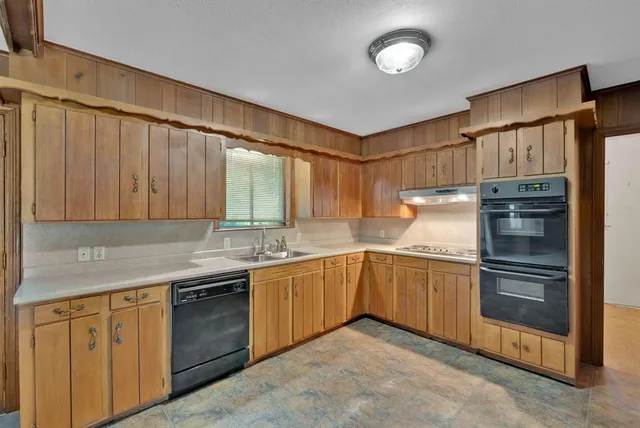 a kitchen with stainless steel appliances granite countertop a sink and dishwasher a refrigerator with wooden cabinets