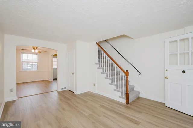 a view of an empty room with wooden floor and stairs