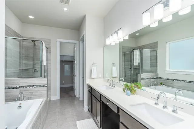 a bathroom with a sink double vanity granite tub shower and a mirror